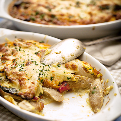 Pork and Bacon Sausages Gratin with Potatoes, Grilled Vegetable and Fresh Herbs